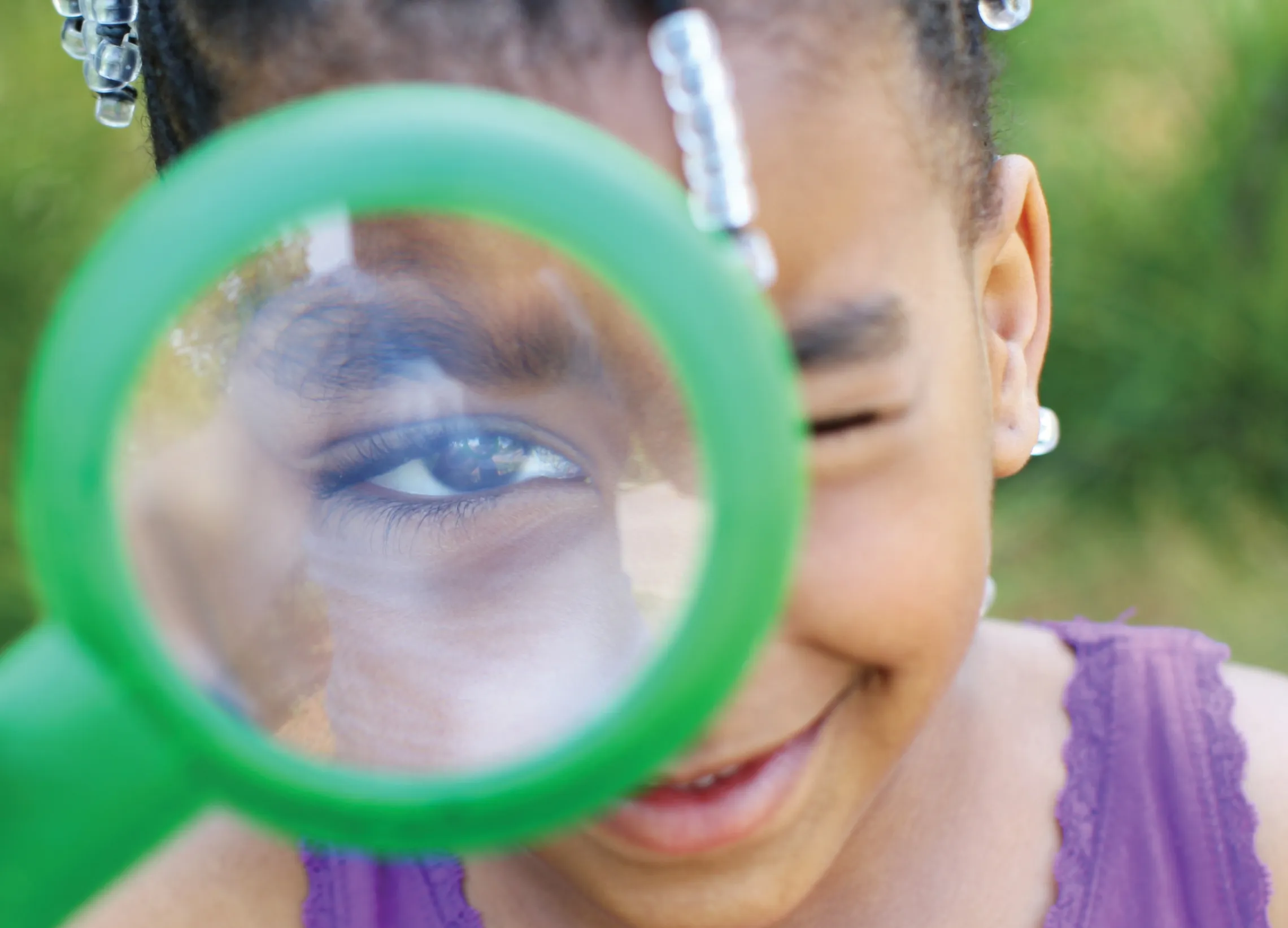 Girl looking through a green magnifying glass